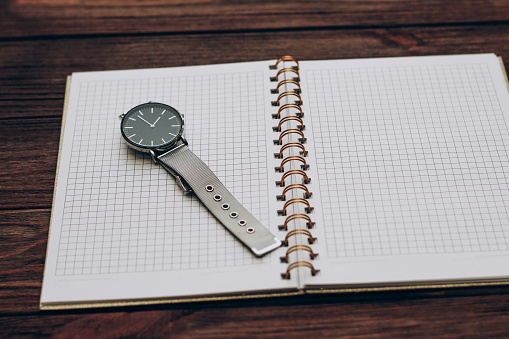 Open notebook diary with clock with black dial, time management concept.