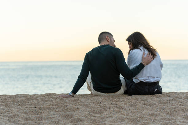 istock Man consoling her friend while sitting on the sand at the beach 1466424079