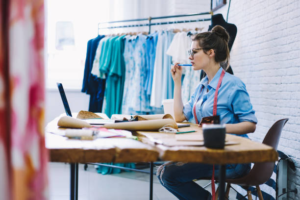 istock Focused dressmaker reading mail on laptop in modern workshop 1466426315