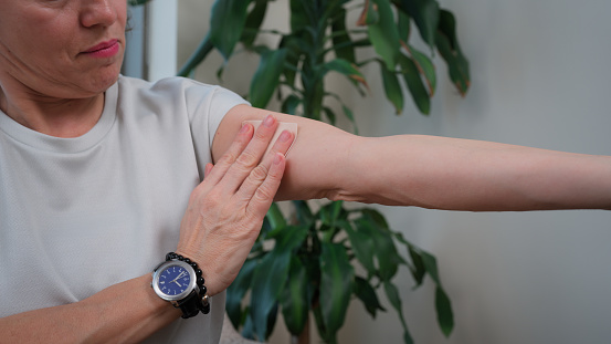 A woman is applying a hormone replacement therapy band on her arm.