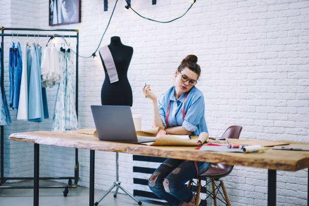 istock Focused dressmaker thinking about new order at table in workshop 1466426497