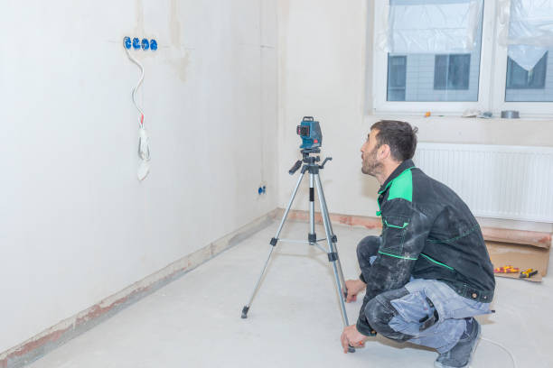 l’homme fait des réparations dans un nouvel appartement. le constructeur nivelle les murs à l’aide du niveau laser - laser work tool projection red photos et images de collection