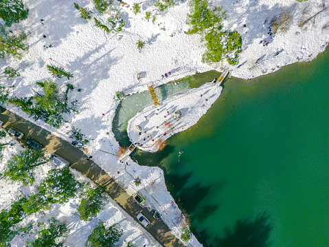Aerial drone top down photo of snowy  Parnitha Mountain and lake Mpeletsi with a small wooden bridge in Ippokrateios Politia, Athens, Attica, Greece at winter