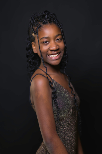 Portrait of a pretty young black girl with braided hair wearing a party dress.