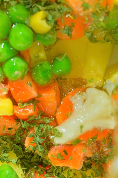 istock Close-up fresh soup vegetables with carrots, peas, cauliflower, corn, chopped potatoes and parsley on white background. Soup vegetables with carrots, peas, cauliflower, corn chopped potatoes and parsley in boiling water on white background, close-up. Vert 1466429679