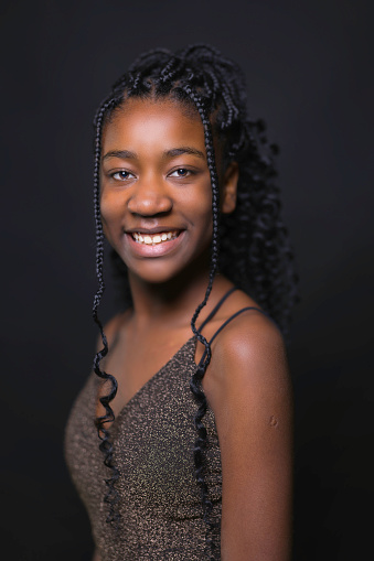 Portrait of a pretty young black girl with braided hair wearing a party dress.