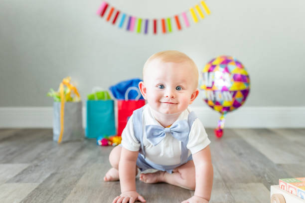 Cute 1 year old baby boy celebrating his first birthday with presents and balloon stock photo