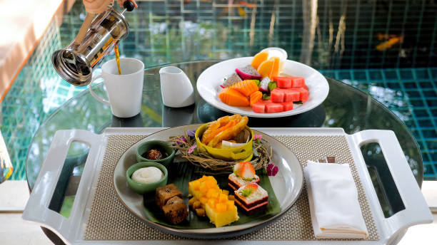 istock Tropical desserts, cakes, and fruits on a table set with plates. 1466430438