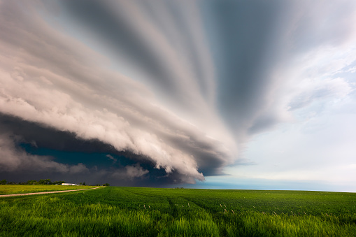 Dramatic storm clouds from a supercell thunderstorm over a field of green grass near Wall, South Dakota.