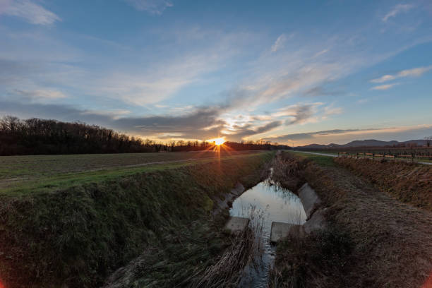 istock Panoramic view in backlight of a natural countryside environment at sunset, under a partially clear and light-blue sky. 1466432660
