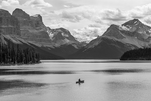 A solitary adventurer on a canoe trip in black and white on Maligne Lake, Canadian Rockies, Jasper national park, Alberta, Canada.