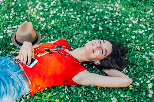 Woman lying down in the grass and listening to music