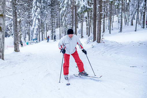 A man in a red and white ski outfit is skiing.