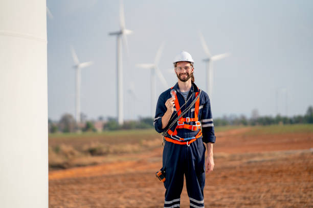 istock Smart engineer or technician man stand with holding light bulb and look at camera with background of windmill or wind turbine and blue sky in concept of green energy to safe the earth. 1466437965