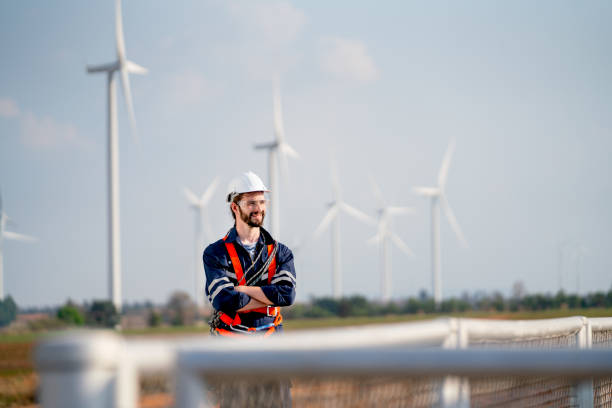 istock Smart engineer or technician man stand with arm crossed and look to right side with background of windmill or wind turbine and blue sky in concept of green energy to safe the earth. 1466437967