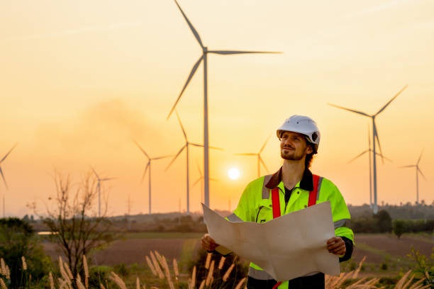 istock Caucasian engineer or technician man stand with holding drawiing paper and look to left side and stand in front of windmill or wind turbine cluster with sunset and warm light. 1466440271