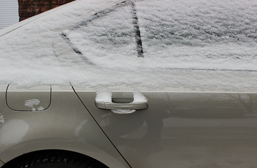 Rear door of a vehicle with snow on the window and a frozen door handle