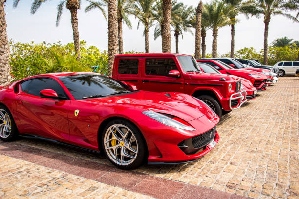 dubaï, émirats arabes unis, le 10 février 2021: une ferrari rouge à côté d’autres voitures modernes luxueuses et élégantes garées près de l’hôtel à dubaï. - luxury sports car red supercar photos et images de collection