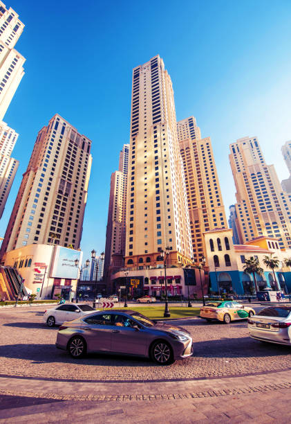 dubai, vereinigte arabische emirate 5. februar 2021: straßenszene mit autos an einer kreuzung gegen die wolkenkratzer am berühmten stadtteil jumeirah beach in dubai, vereinigte arabische emirate. - dubai united arab emirates traditional culture camel stock-fotos und bilder