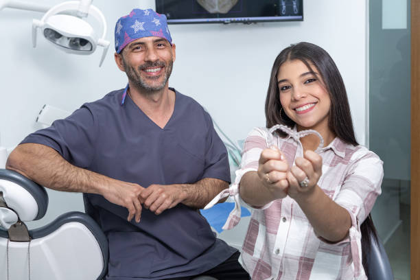 glückliche ethnische teenager-mädchen zeigen zahnspangen in der nähe von zahnarzt in der klinik - teenager dentist patient cheerful stock-fotos und bilder