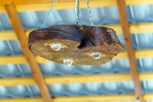 The chandelier is made of a cut tree trunk with light bulbs and is suspended on chains