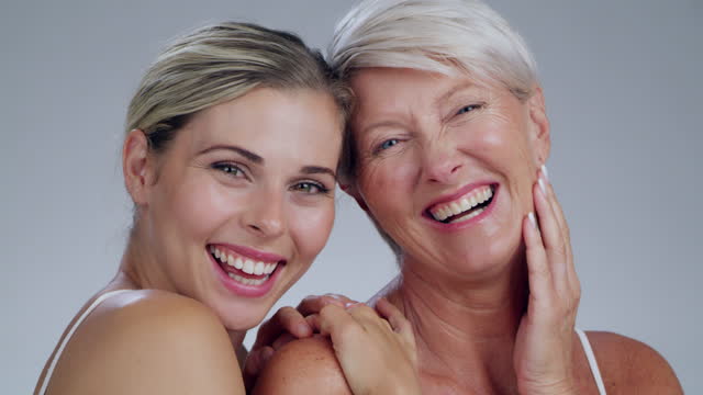 Face, beauty or skin with a mother and daughter in studio on a gray background to promote antiaging. Portrait, family or skincare cosmetics with a woman and adult child bonding over natural treatment