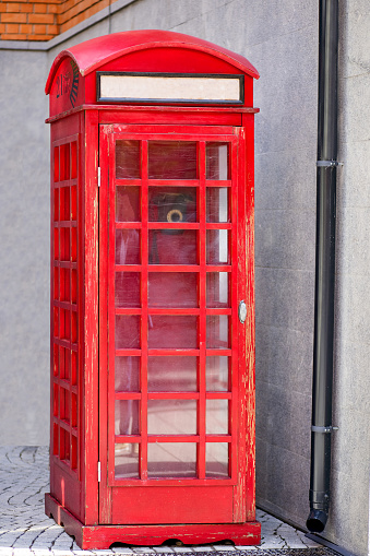 Red telephone booth on the streets of London. A traditional red British telephone booth with a place for text instead of the inscription telephone. Vertical photo of a historic British telephone booth