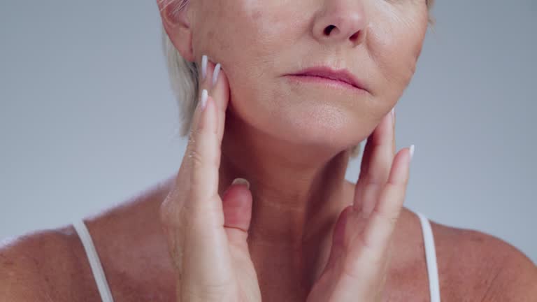 Skincare, wrinkles and senior woman in a studio touching her face for a anti aging skin routine. Beauty, self care and elderly female model doing a cosmetic wrinkle treatment by a gray background.