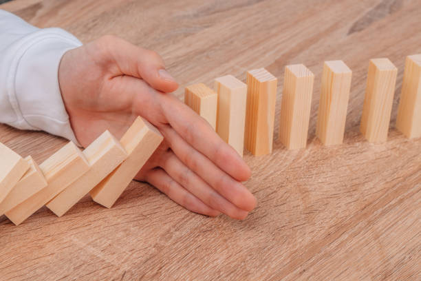 istock hand stops falling dominoes or wooden puzzle 1466460024