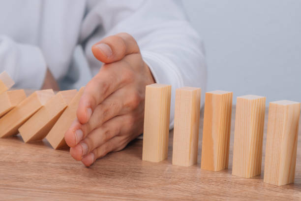 istock hand stops falling dominoes or wooden puzzle 1466460038