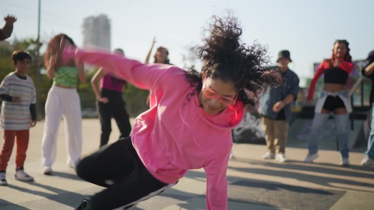 Young woman breakdancing during street party with her friends outdoors