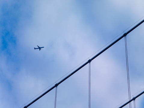 Airplane passing between suspension bridge ropes