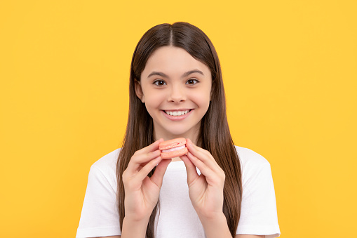 smiling cheerful child with dessert bakery. kid hold french macaron. macaroon cookie. confectionery. sweet french cakes. teen girl dental care. sweet tooth. yummy. patisserie biscuits.