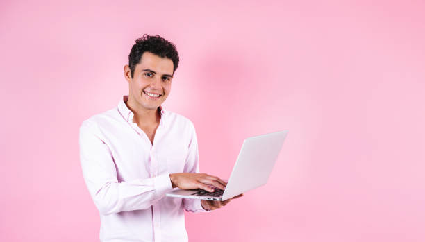 istock young hispanic business man using computer or laptop and smiling at camera on pink background in Mexico Latin America 1466471897