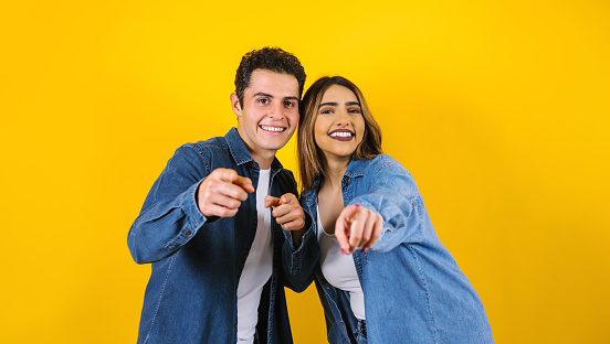 young hispanic couple portrait having fun on yellow background in Mexico Latin America