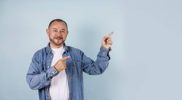 retrato do homem sênior latino apontando um espaço de cópia no fundo azul no méxico américa latina - mexico only men senior men mature men - fotografias e filmes do acervo