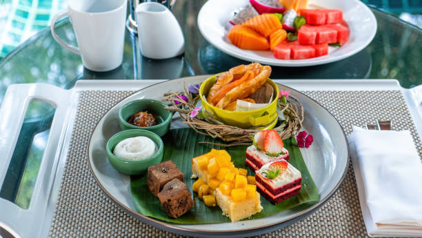 istock Tropical desserts, cakes, and fruits on a table set with plates. 1466472986