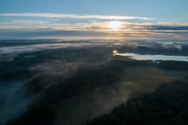 Foggy morning on a beautiful lake surrounded by forests and fields. A small village located near a lake in fog and morning sun. stock photo