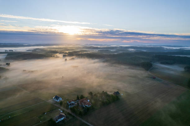 Foggy morning on a beautiful lake surrounded by forests and fields. A small village located near a lake in fog and morning sun. stock photo