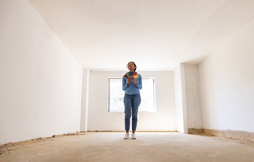 Happy African American woman remodeling her house and choosing a color for the walls