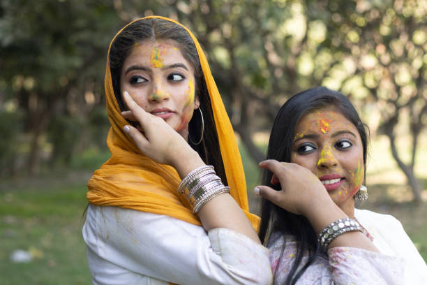 Two young girls sisters friends family celebrating enjoying holi festival of colors colours outdoor in a park a popular hindu festival celebrated across india with gulal abeer color powder stock photo