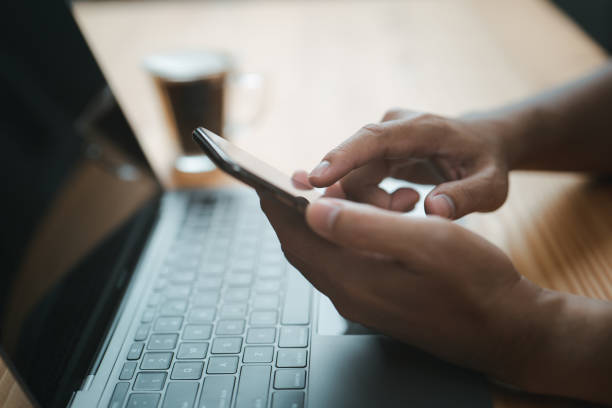 istock A closeup view of male hands touching a mobile phone man using his smartphone while sitting at the wooden table 1466481154