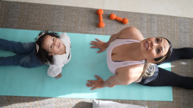 Mother exercising with her daughter in the living room at home