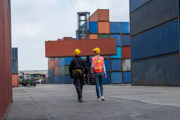 istock Industrial worker works with co-worker at overseas shipping container yard . Logistics supply chain management and international goods export concept . 1466482430