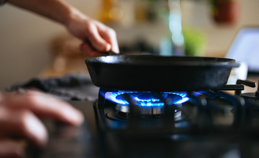 An anonymous man preparing lunch in a pan in the kitchen.