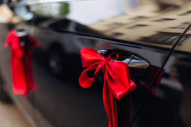 istock black car is decorated with a red bow. car door. close up 1466485517
