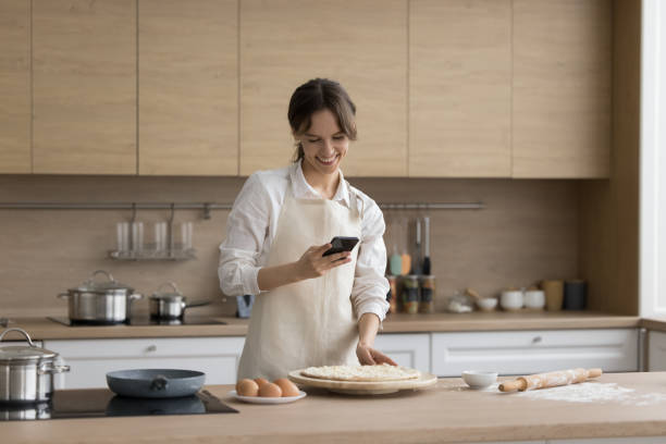 istock Happy young cook girl wearing apron, using mobile phone 1466487863