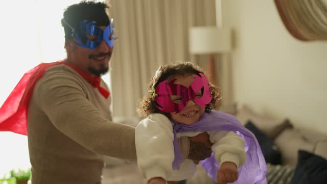 Father and daughter playing superhero in the living room at home