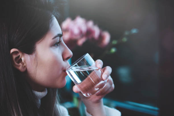 jeune femme buvant un verre d’eau - water women glass healthy eating photos et images de collection