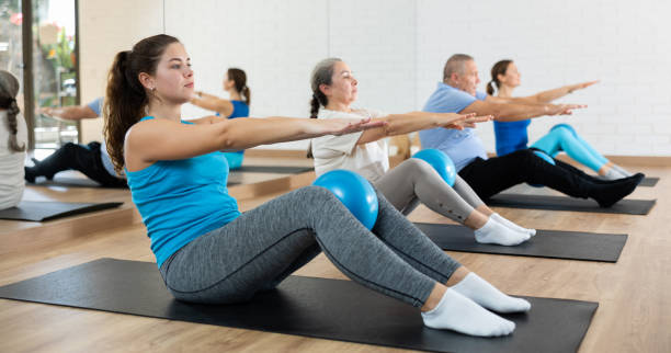 istock People of different ages pressing core and clutching mini Pilates balls between legs during Pilates training together 1466492975